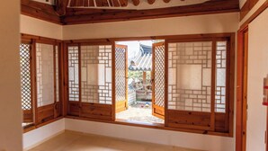 Una tradizionale stanza giapponese con pavimento in tatami, porte scorrevoli in legno e vista su un giardino tradizionale.