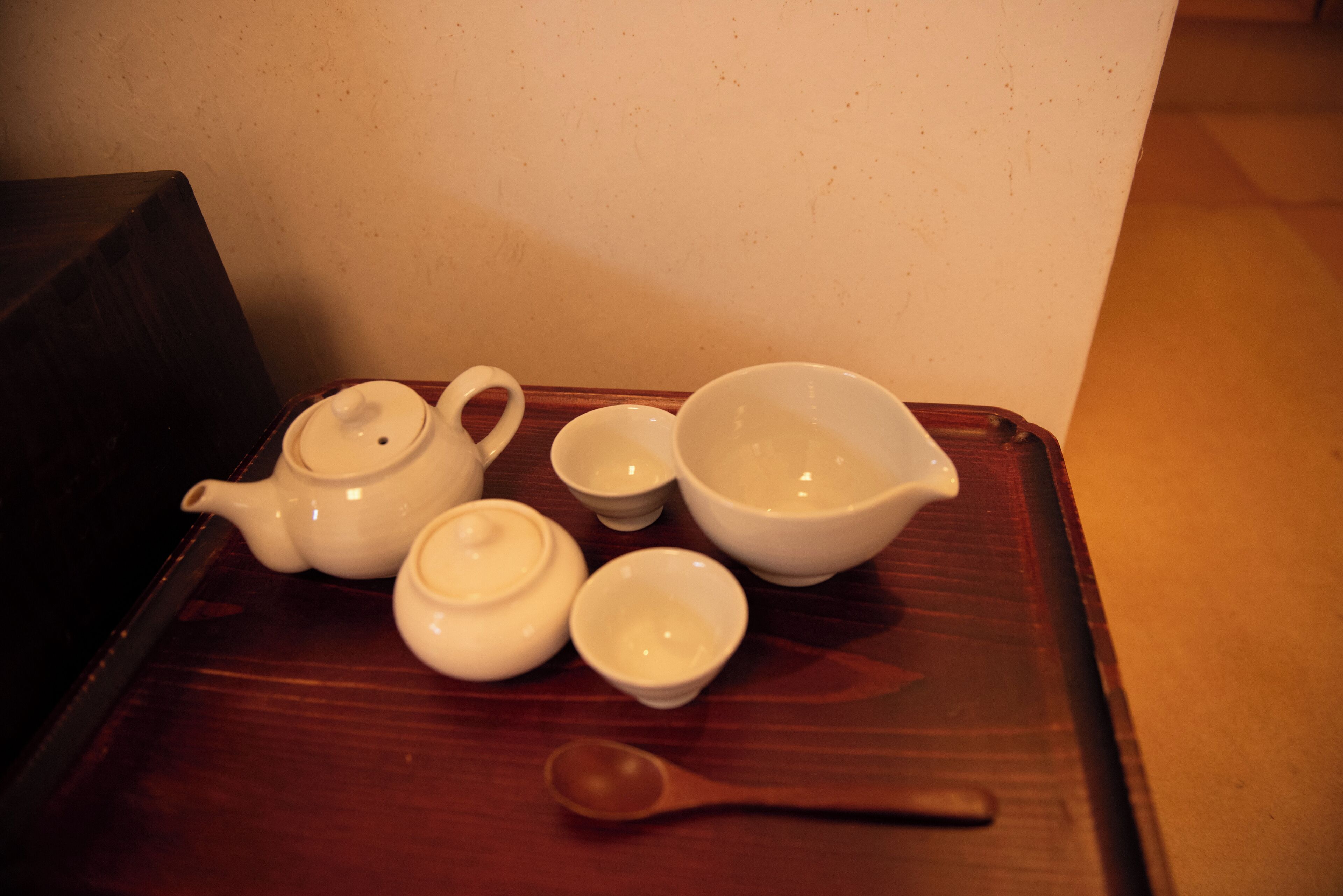 A set of white ceramic tea utensils on a wooden tray.