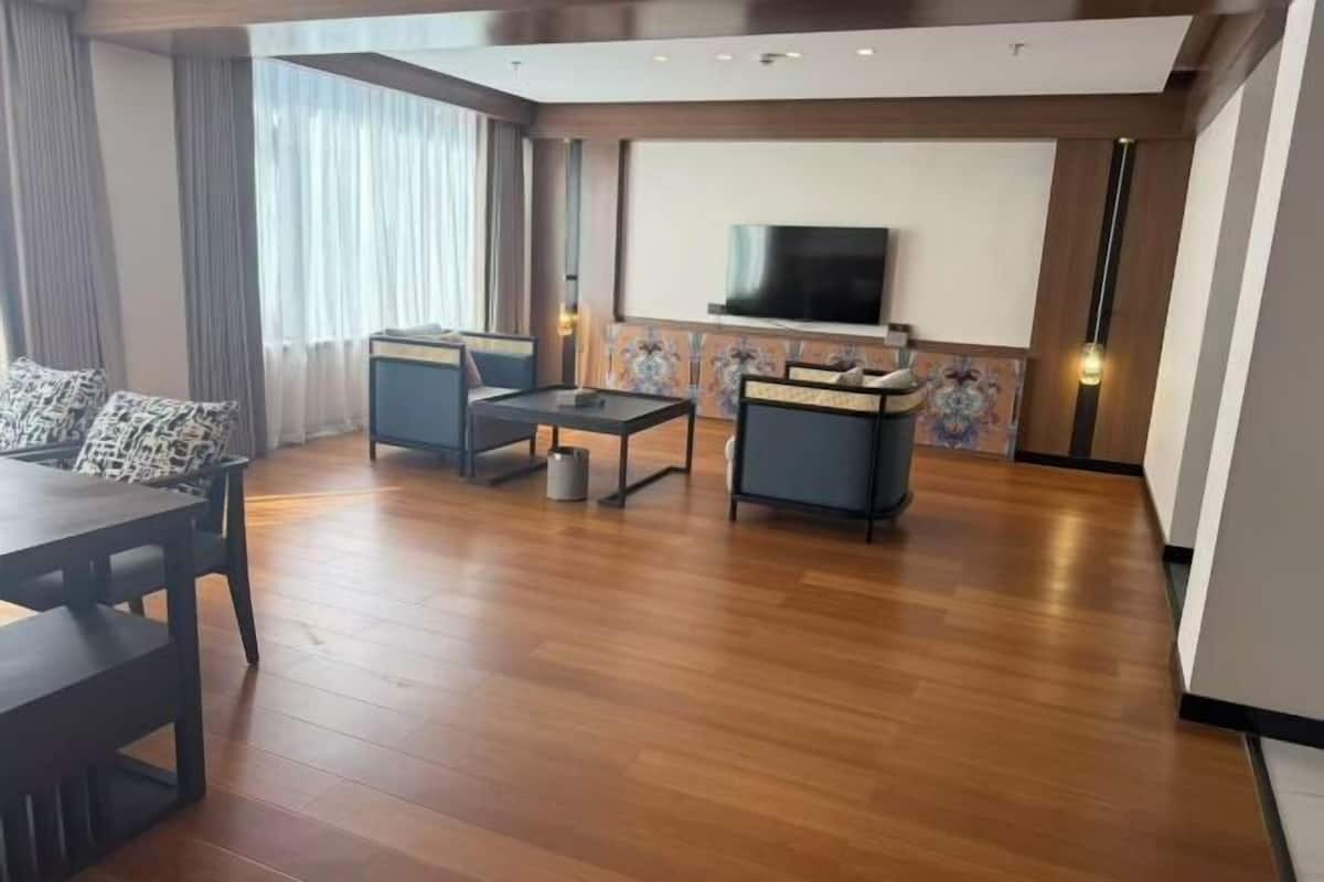 A modern living room with a wooden floor, a TV mounted on the wall, and two sofas.