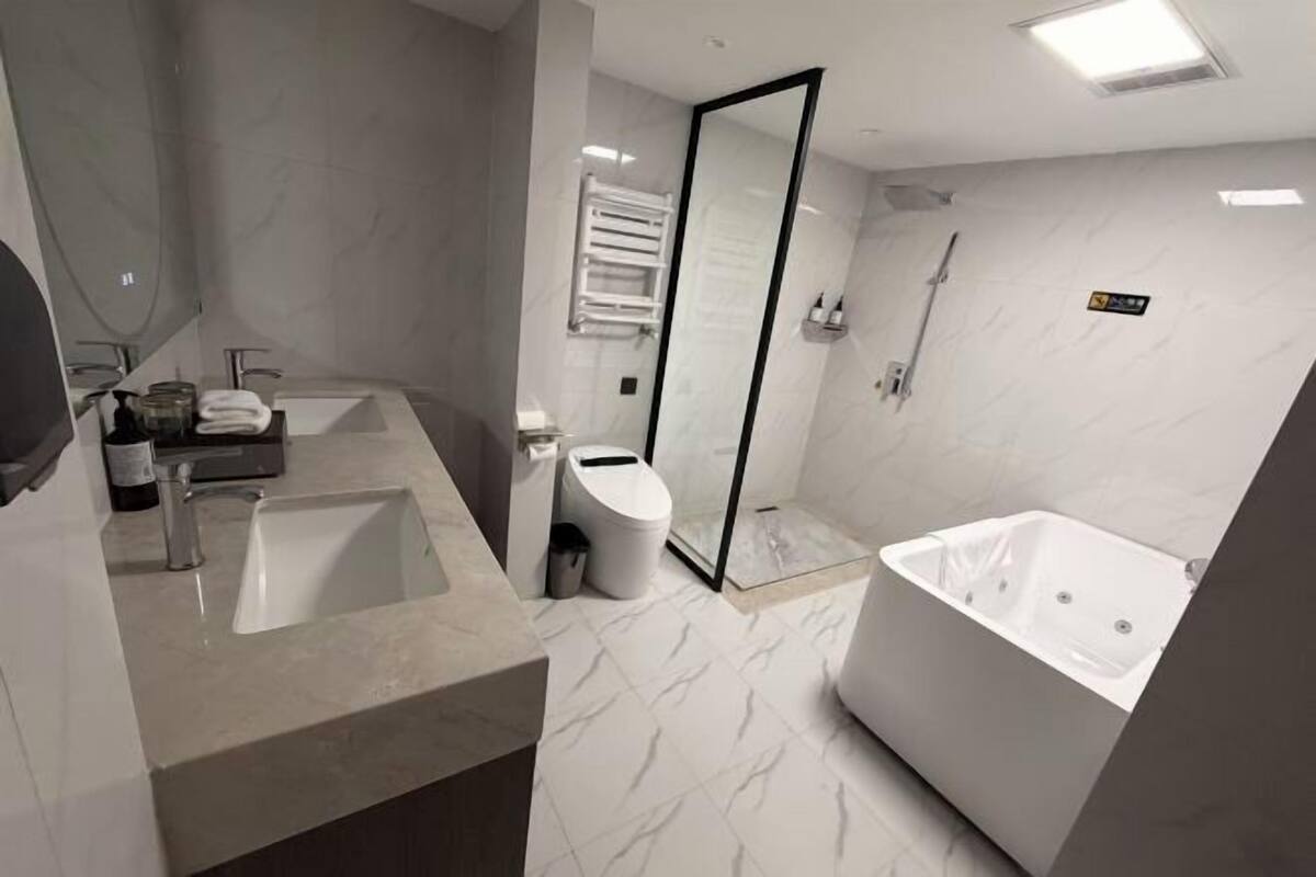 A modern bathroom with a large bathtub, a separate shower area, and a vanity with a sink and mirror.