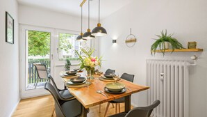 Ein Essbereich mit einem Holztisch, gedeckt für vier Personen, schwarzen Stühlen und Pendelleuchten.