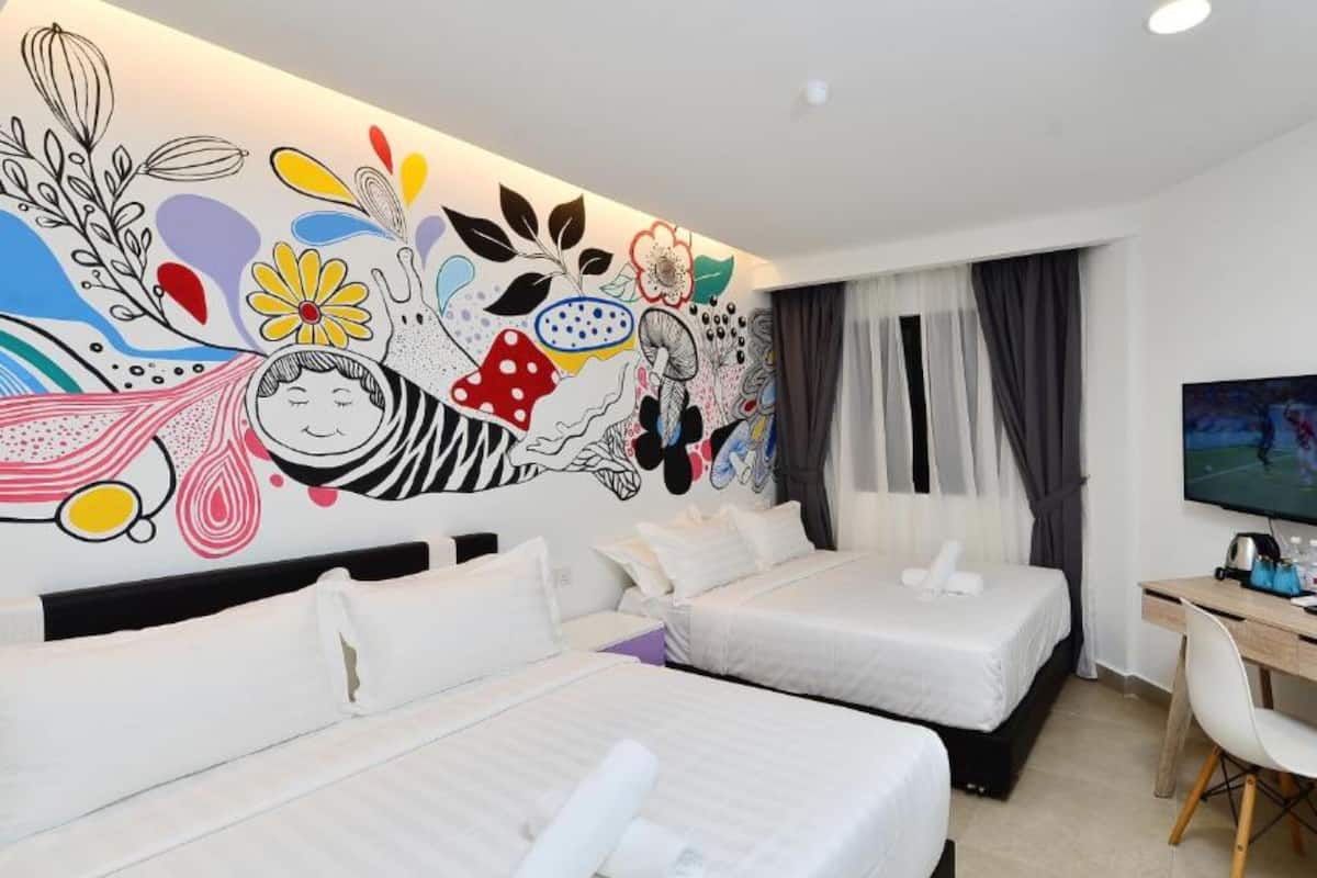 Habitación de hotel con dos camas, un escritorio y una televisión.