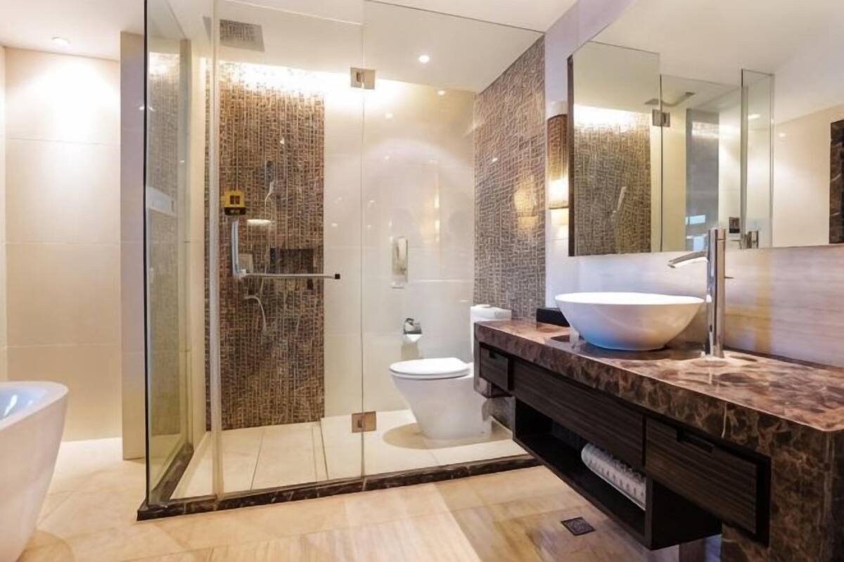 A modern bathroom with a glass-enclosed shower, a white toilet, and a large vessel sink with a marble countertop.