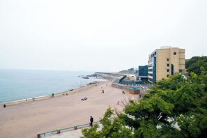 A beach with a promenade, a building with a flat roof, and a clear sky. - Grand Metropark Qingdao (Qingdao)
