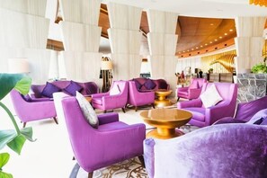 A lobby with purple sofas, a coffee table, and a large plant. - Grand Metropark Qingdao (Qingdao)