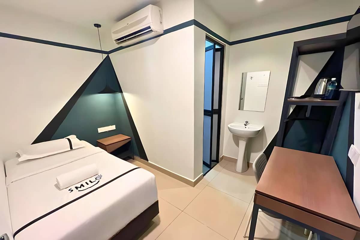 Een hotelkamer met een bed, bureau, wastafel en een airconditioning.