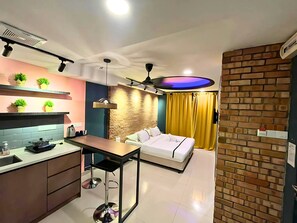 A modern kitchen with a dining area, a bed, and a brick accent wall. - Smile Hotel Titiwangsa Pekeliling Sentul (Kuala Lumpur)