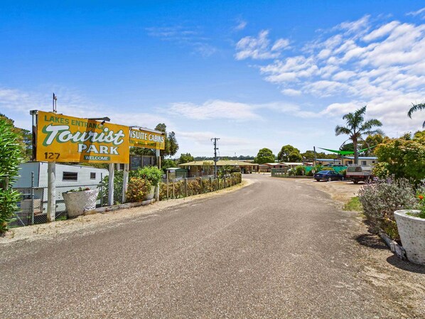 A road leading to a park with a sign for 'Tourist Park' and 'Insuite Cabins'. - Lakes Entrance Tourist Park (Lakes Entrance)
