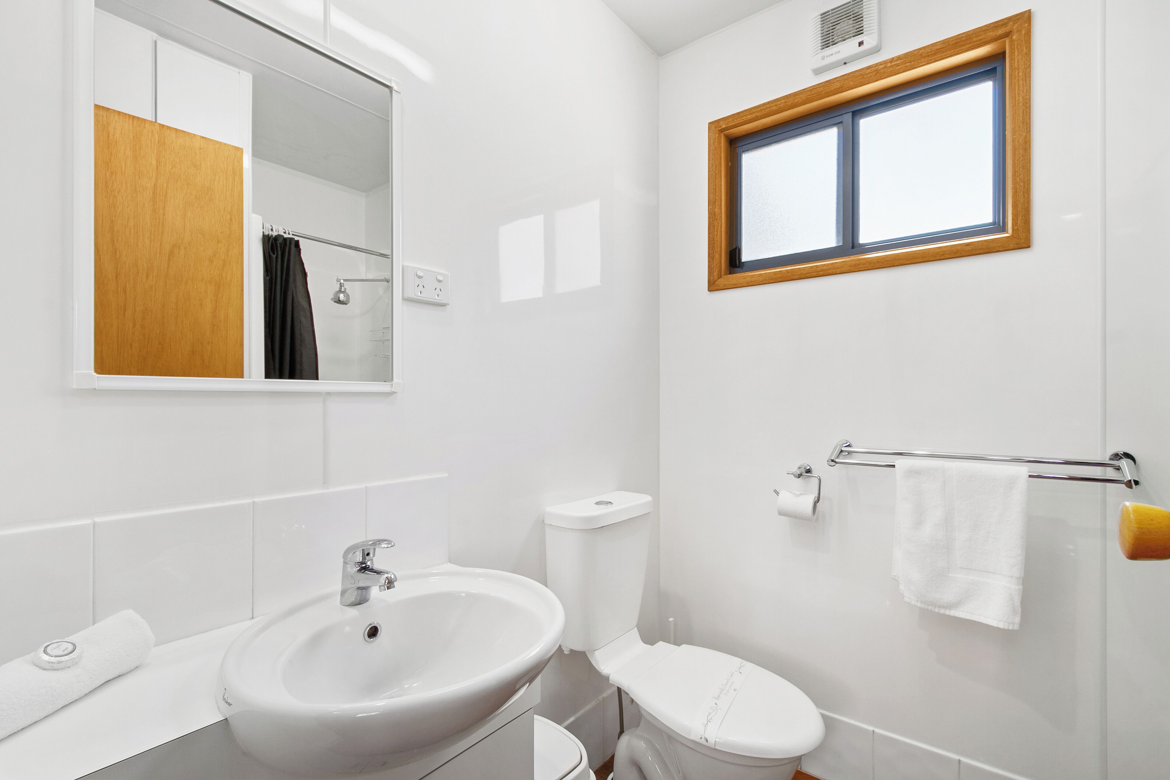 A modern bathroom with a white sink, toilet, and mirror.