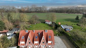 Een groot gebouw met een rood dak, veel ramen en een grasveld op de voorgrond.