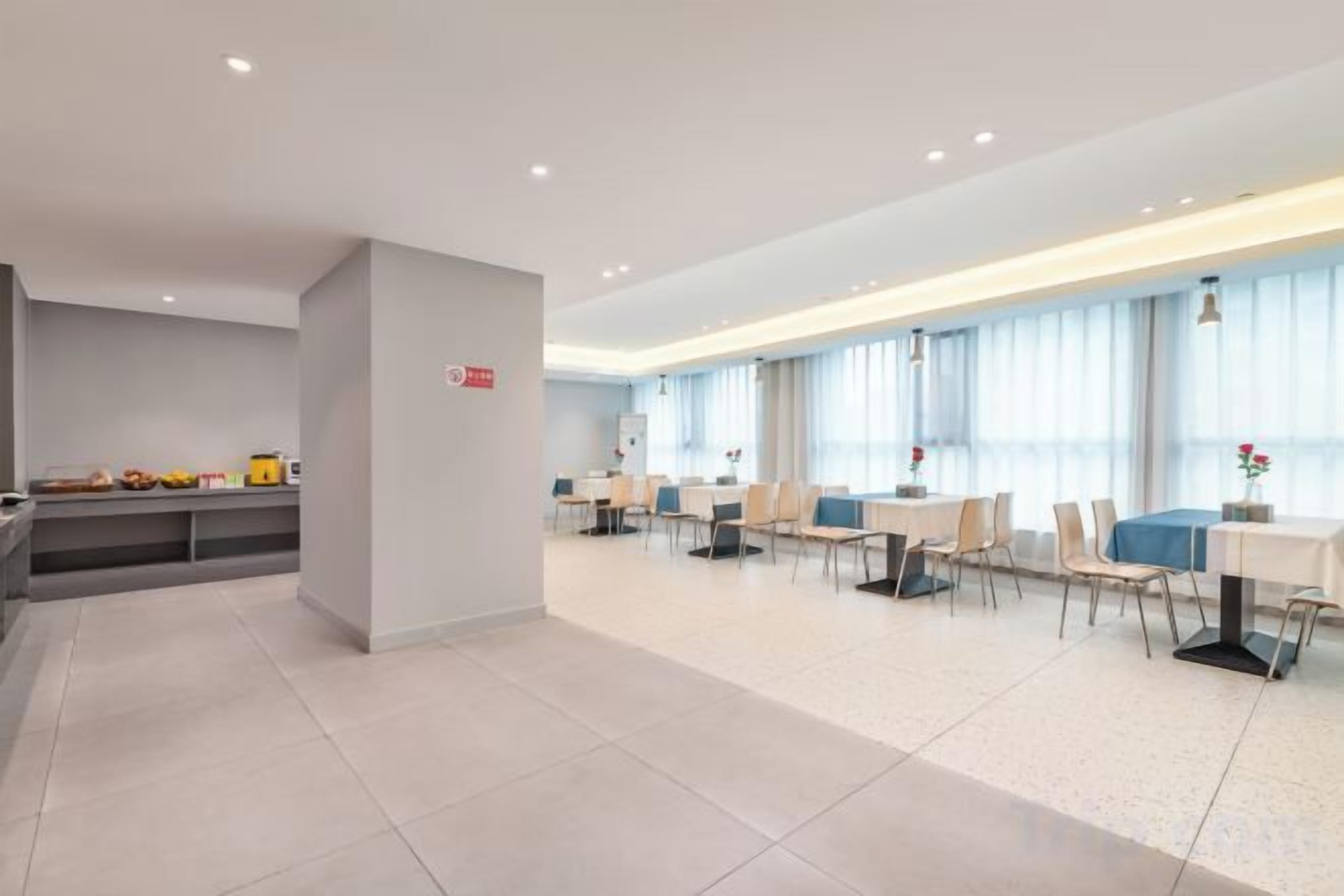 A modern hotel lobby with a reception desk, seating area, and large windows.