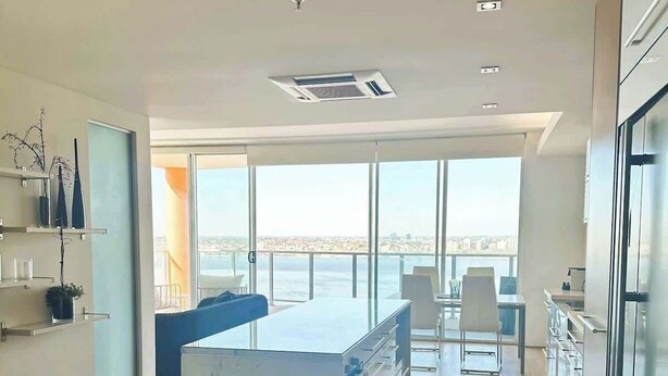 Una cocina moderna con una isla grande, suelo de madera y vista al mar.