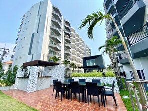 Residents enjoy balconies with outdoor space and a patio area with a table and chairs surrounded by lush greenery.