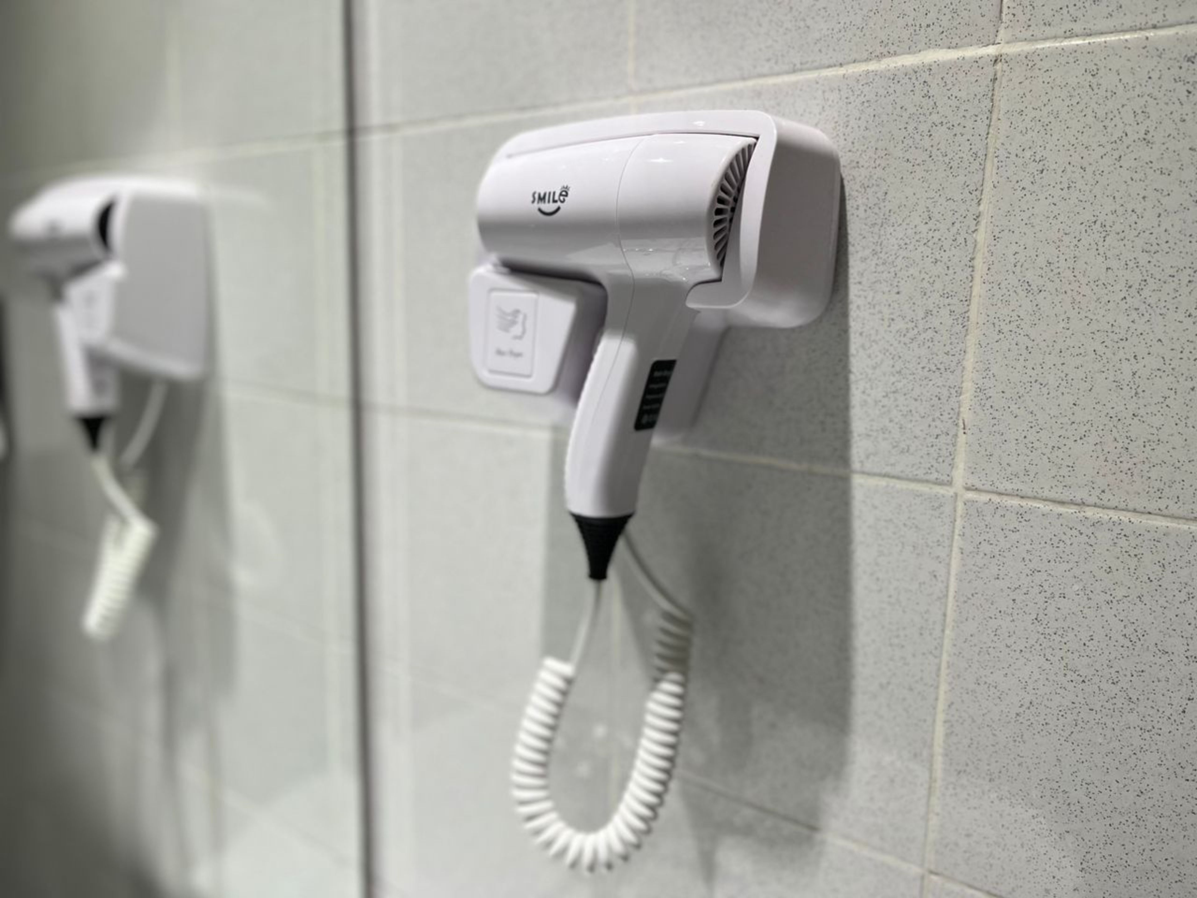 Een haardroger bevestigd aan een betegelde muur.
