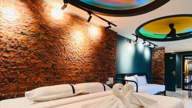 Una habitación de hotel con pared de ladrillo, cama con ropa blanca y un elemento circular en el techo.