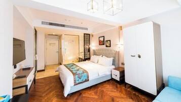 Una habitación de hotel con cama, armario, televisor y escritorio.