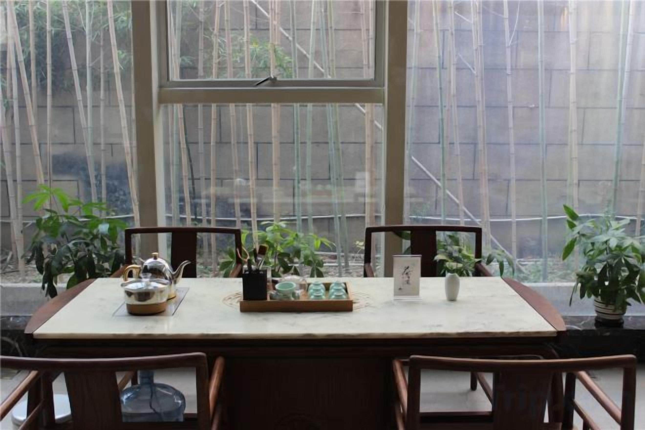 Una mesa con sillas, un ventanal y plantas en macetas.