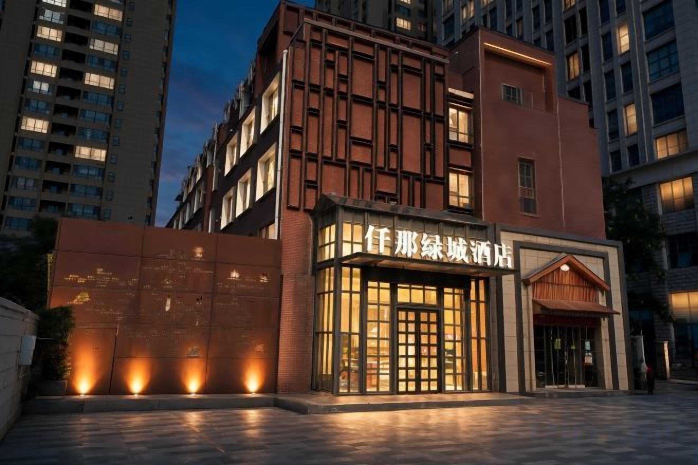 A hotel with a modern facade, illuminated entrance, and a visible name sign.
