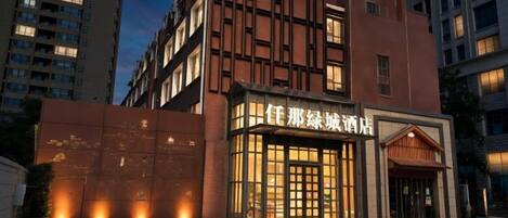 A hotel with a modern facade, illuminated entrance, and a visible name sign.