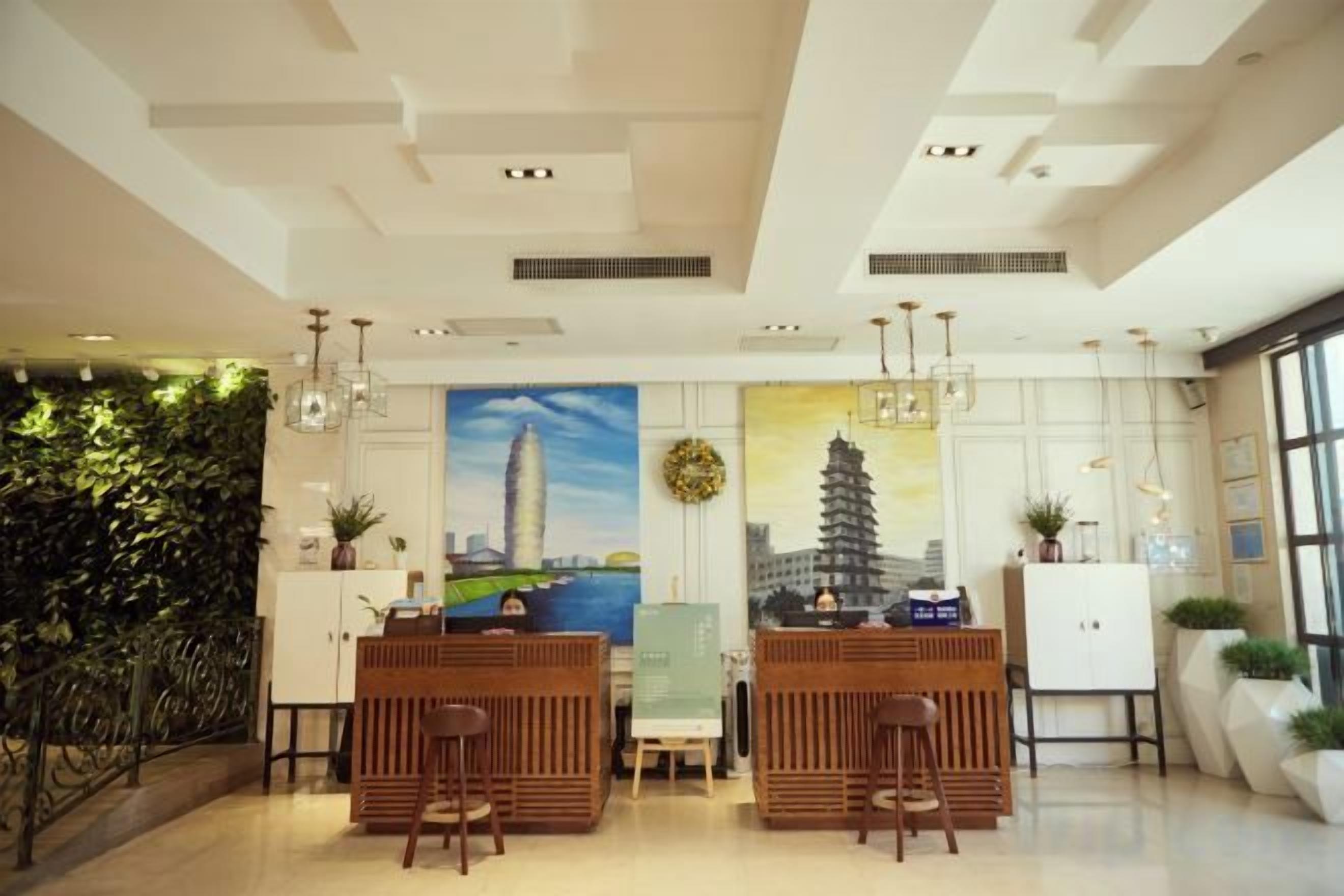 A hotel lobby with a reception desk, seating area, and artwork on the walls.