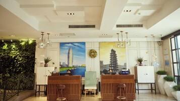 A hotel lobby with a reception desk, seating area, and artwork on the walls.
