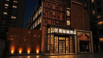 Un hotel con fachada moderna, entrada iluminada y un letrero con caracteres chinos.