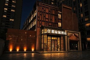 Un hotel con fachada moderna, entrada iluminada y un letrero con caracteres chinos.