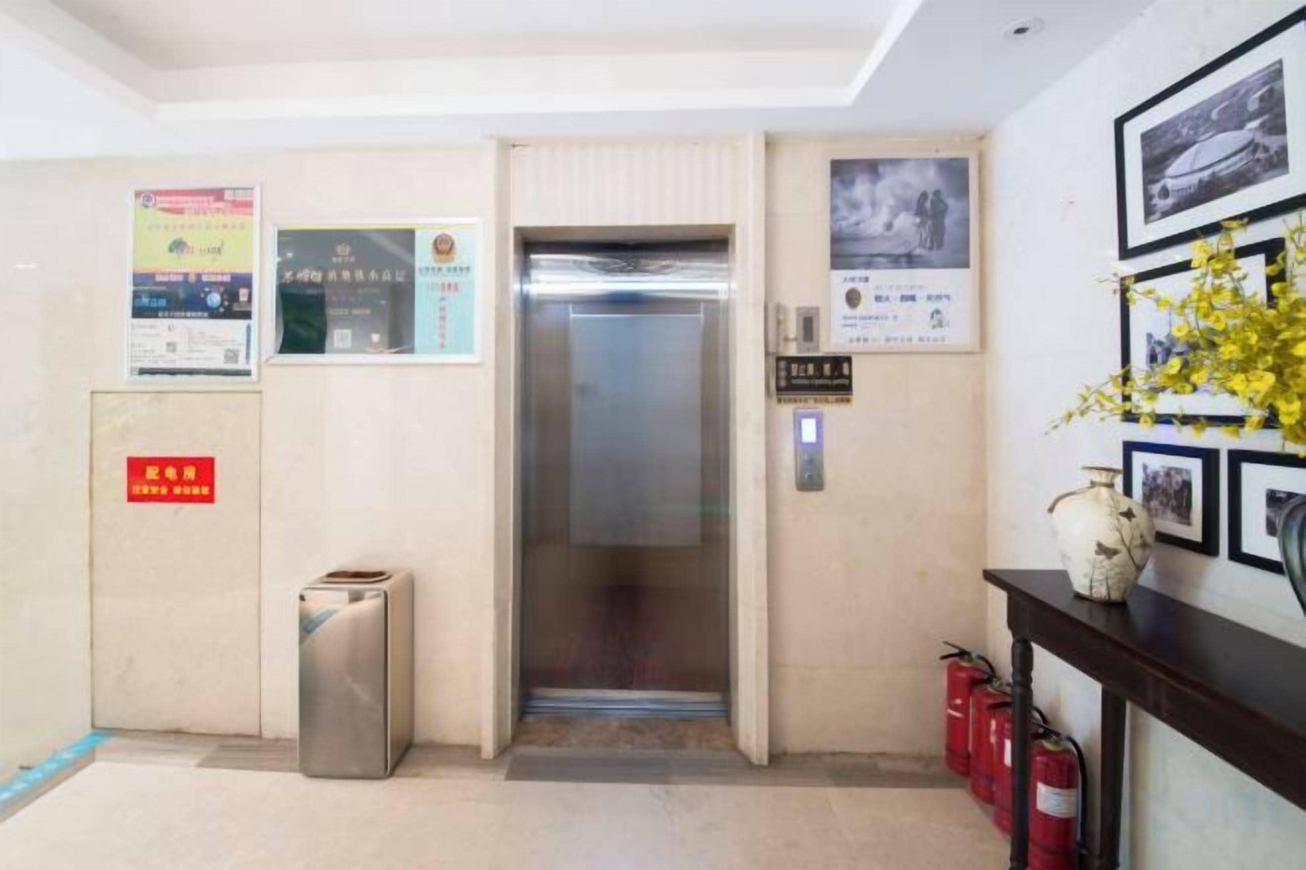 Un ascensor en un edificio, con un extintor y un basurero cerca.