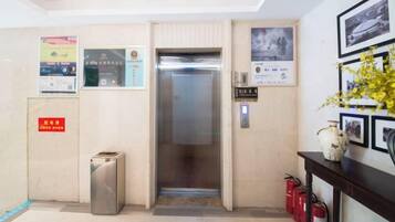Un ascensor en un edificio, con un extintor y un basurero cerca.