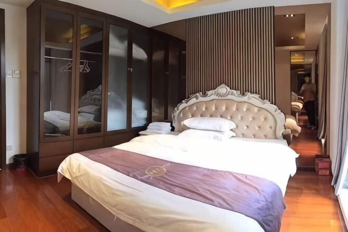 A bedroom with a large bed, a wardrobe, and a view of a corridor.
