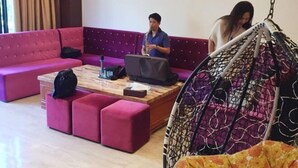 Un'area lounge moderna con un divano viola, un tavolino in legno e una sedia sospesa.