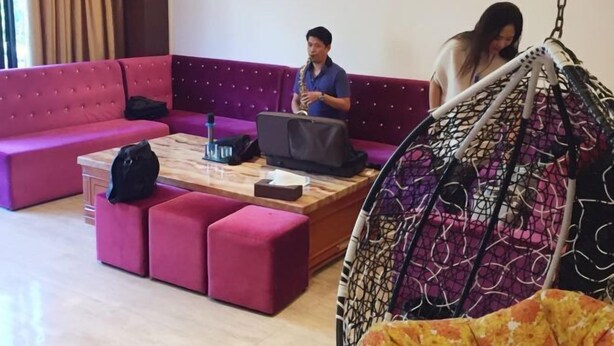 Et moderne loungeområde med en lilla sofa, et træbord og en hængestol.
