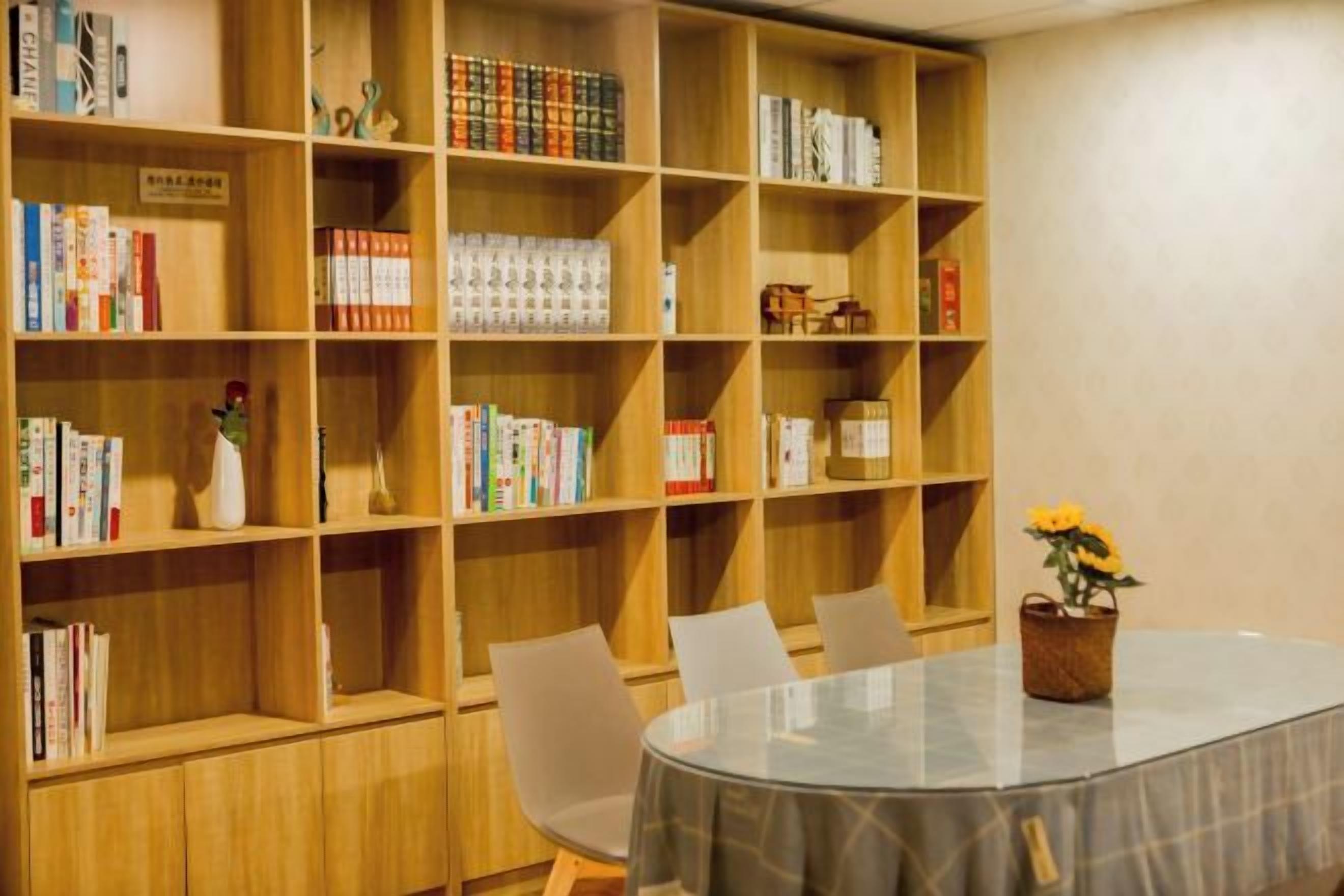 Una habitación con una mesa redonda, sillas y una estantería llena de libros.