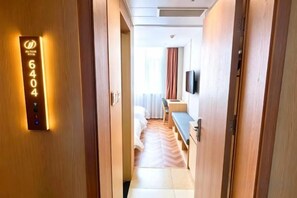 A hotel corridor with a digital room number display, a bed, a desk, and a television mounted on the wall. - Jia Yuan Hotel (Jining)