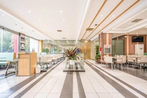 A spacious lobby with a reception desk, seating area, and a large plant centerpiece. - Jia Yuan Hotel (Jining)