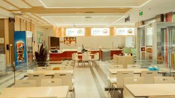 A modern restaurant interior with multiple dining tables and chairs, a kitchen area, and a counter.