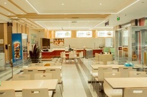 A modern restaurant interior with multiple dining tables and chairs, a kitchen area, and a counter.