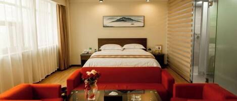 Una habitación de hotel con una cama, una mesita de noche y un sofá rojo junto a una mesa de centro de vidrio.