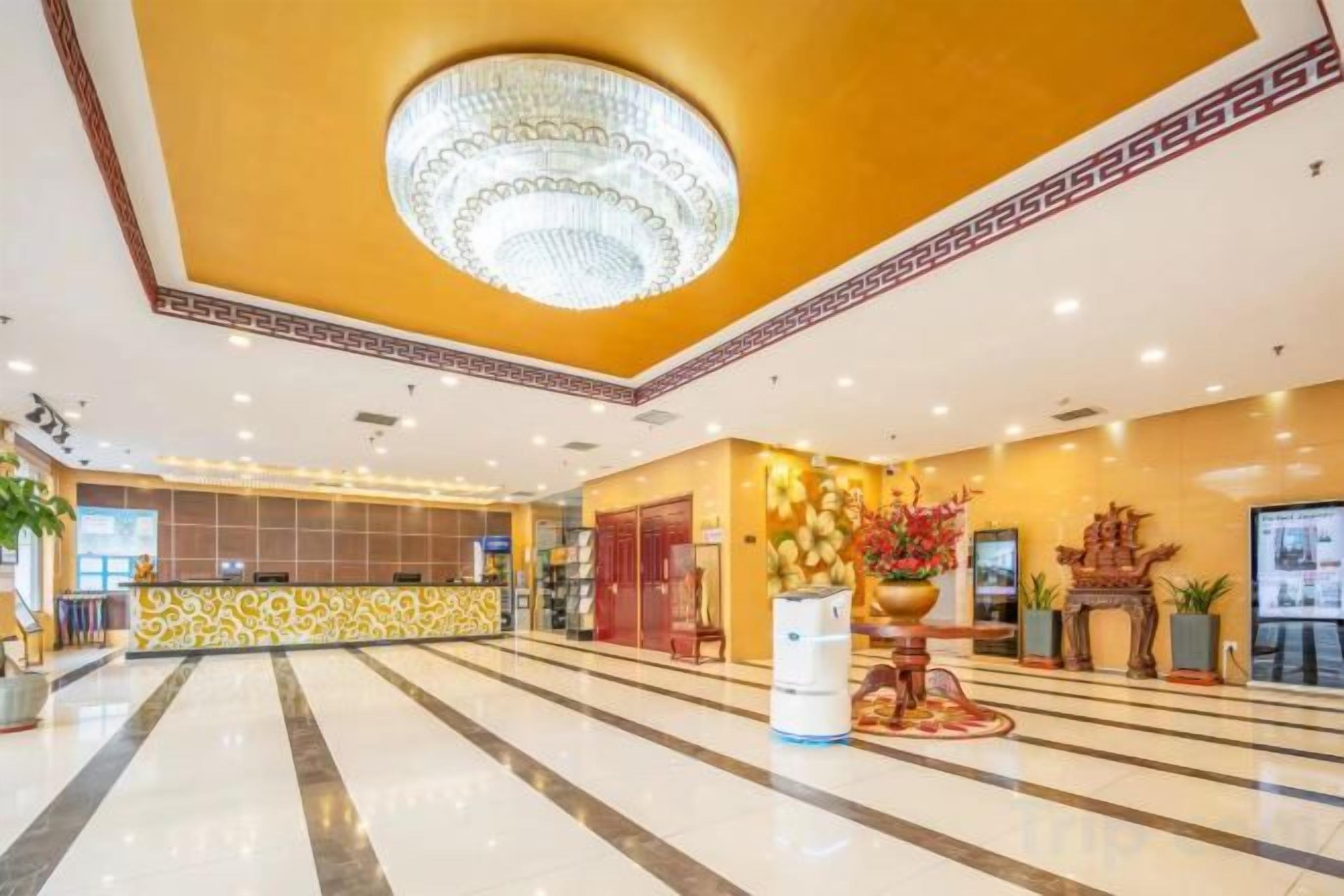 Eine Hotelhalle mit Empfangstresen, einer Chandelüster und einem dekorativen Altar.