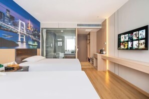 Ein Hotelzimmer mit Bett, Schreibtisch, Fernseher und einem Stadtbild.