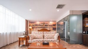 A modern living room with a sofa, coffee table, and a cityscape mural on the wall.