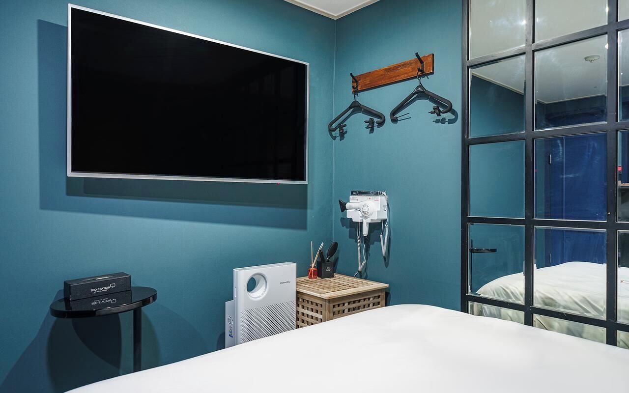 A bedroom with a large TV, a wardrobe, and a window with a view.