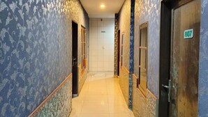A hallway with patterned wallpaper, tiled flooring, and doors with a number sign. - Hotel Labuhan Raya (Medan)