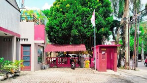 A hotel entrance with a red awning, a security booth, and a paved walkway. - Hotel Labuhan Raya (Medan)