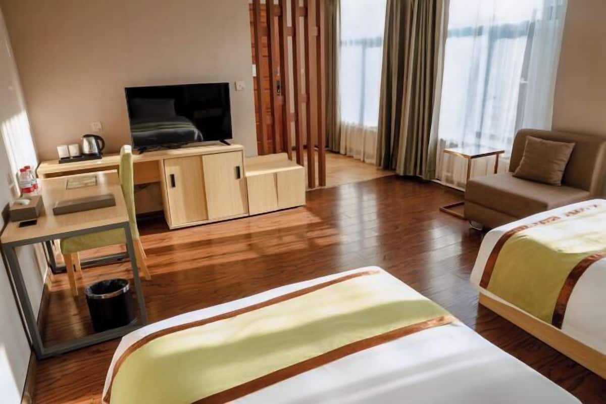 Une chambre d’hôtel avec un lit, un canapé, un bureau avec une télévision et une vue sur l’extérieur.