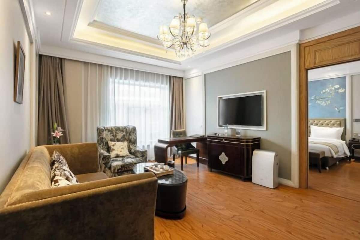 Une chambre d’hôtel équipée d’un canapé, d’un fauteuil, d’une télévision, d’un bureau et d’un lit.