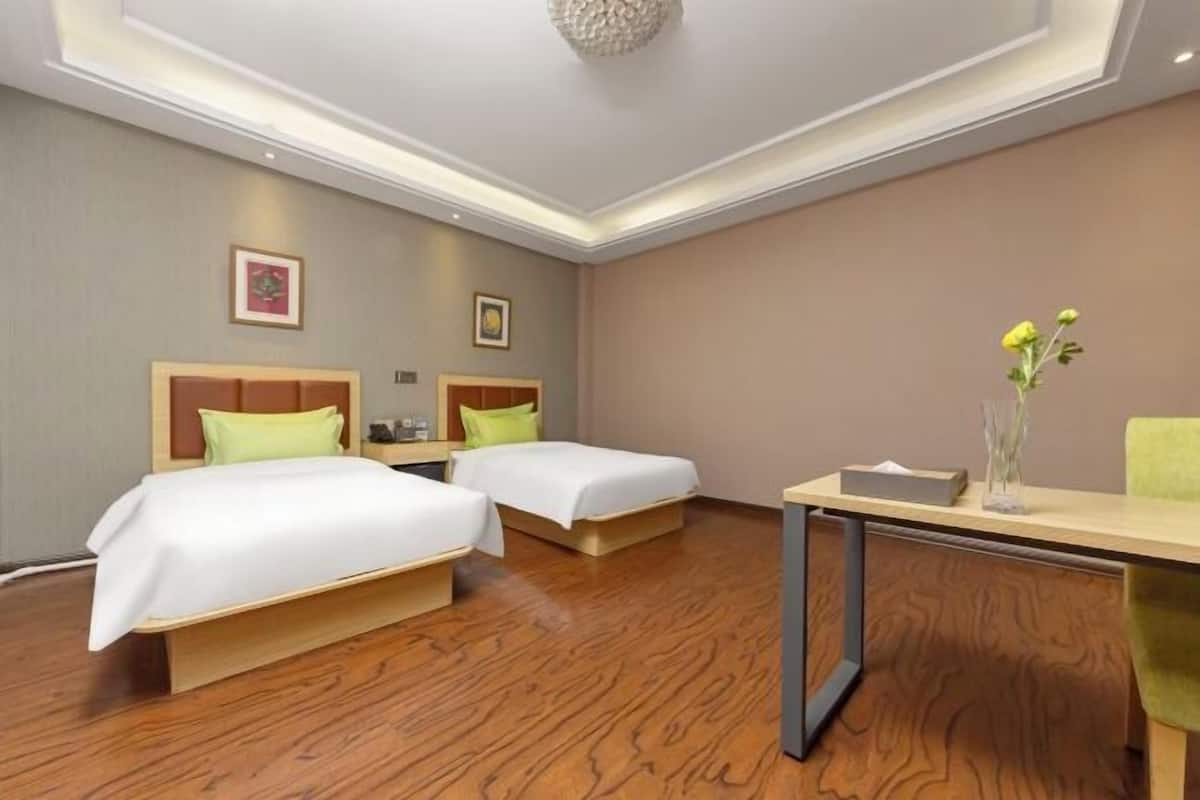 Une chambre d’hôtel avec deux lits, un bureau et une petite table.