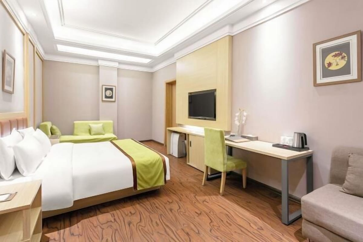 A hotel room with a bed, desk, chair, and television.