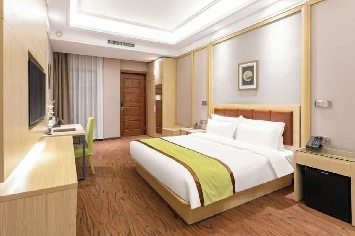 Une chambre d’hôtel comprenant un lit, une table de chevet, un bureau, une chaise et une petite kitchenette.