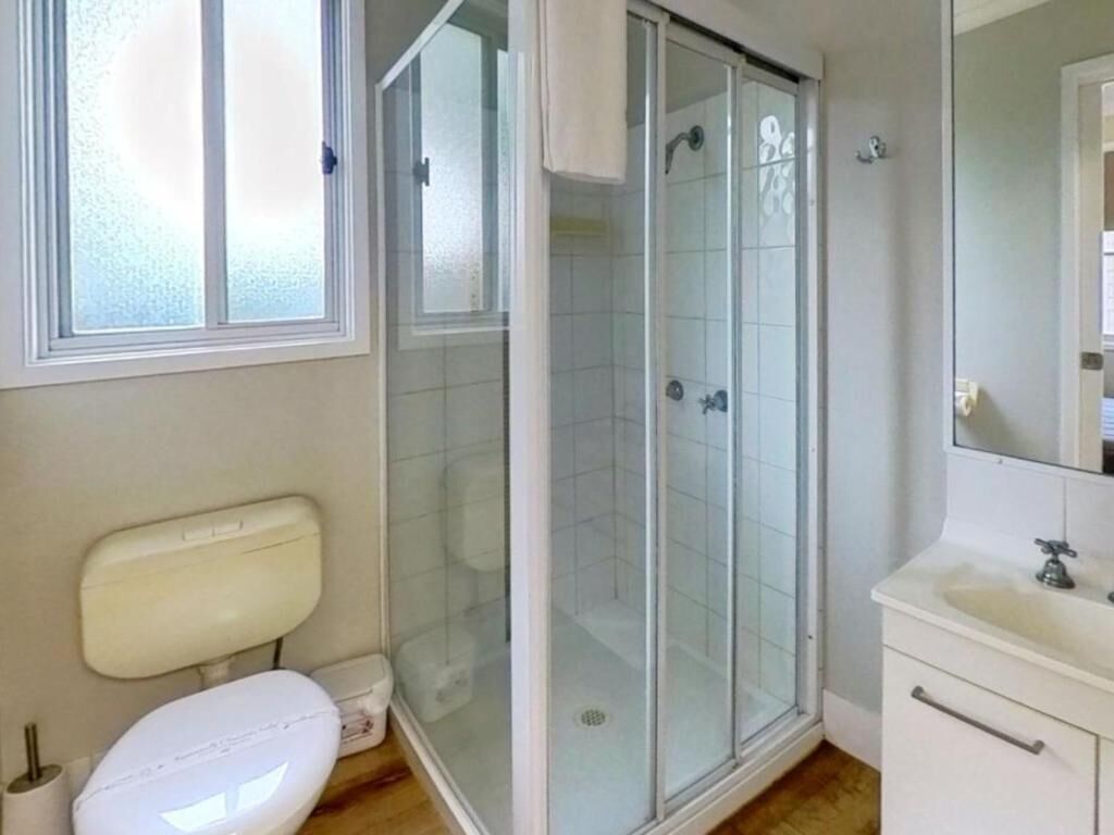 Ein Badezimmer mit Toilette, einer Duschkabine und einem Waschbecken mit Spiegel.